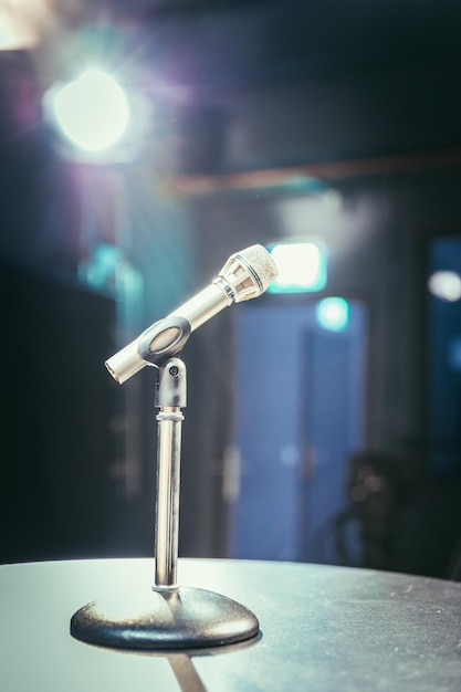 Foto microfone no equipamento de estúdio de gravação e iluminação no fundo desfocado