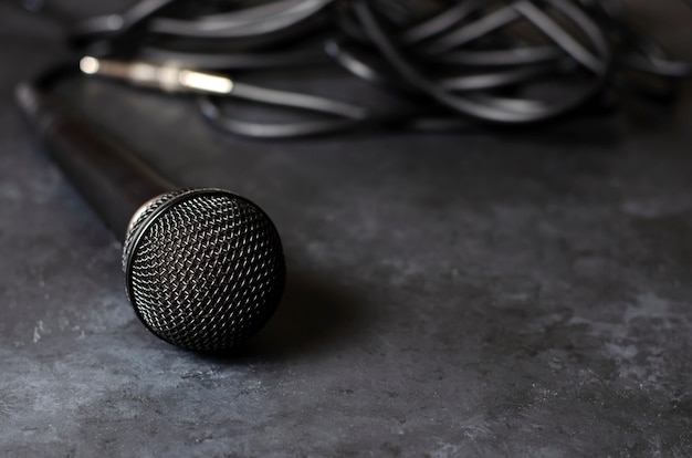 Microfone preto em uma mesa de concreto escura. equipamento para vocais ou entrevistas ou reportagem. copie o espaço