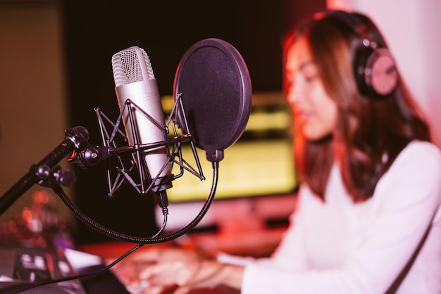 Micrófono de estudio y escudo pop en el micrófono en el estudio de grabación vacío con desenfoque Mujer asiática de fondo. Actuación y espectáculo en el equipamiento del negocio musical.