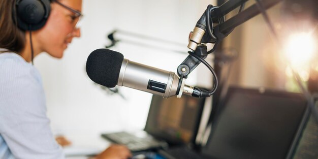 Foto micrófono en un estudio de podcasting joven anfitrión y el equipo de transmisión en el fondo