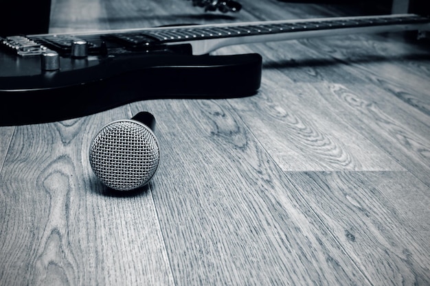 Micrófono y guitarra sobre un fondo de madera en blanco y negro