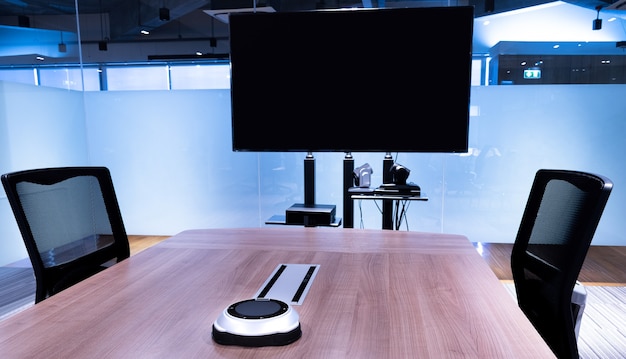 Micrófono inalámbrico portátil en la mesa con televisión de pantalla en blanco en la sala de reuniones