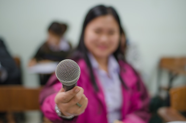 Foto micrófono en una mano de una mujer en un aula