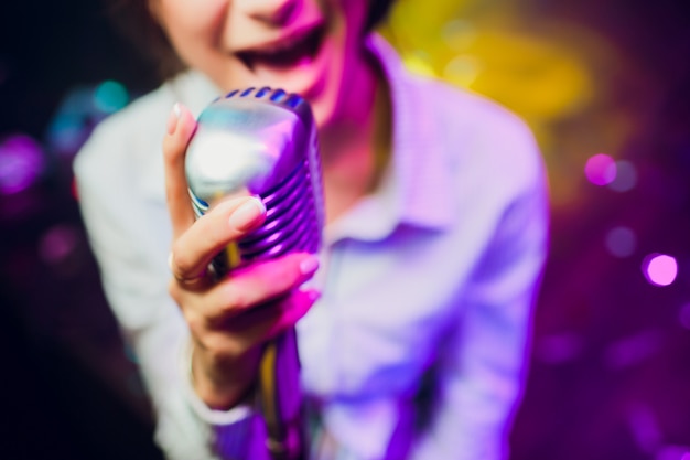 Micrófono moderno para cantar contra un hermoso bokeh de colores borrosos.