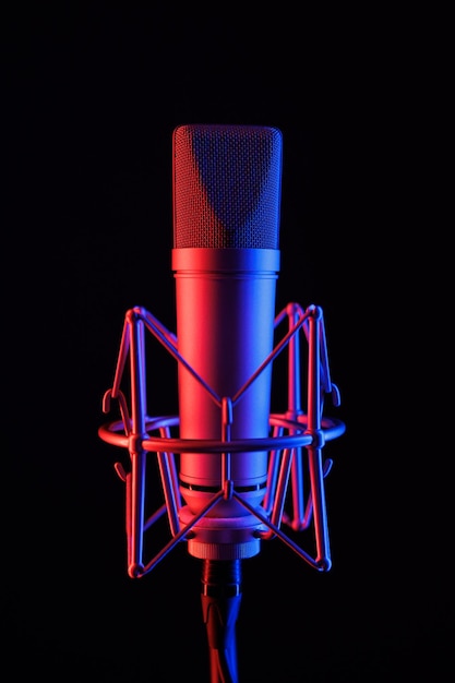 Micrófono sobre un soporte negro con iluminación LED de neón en colores azul y morado en un estudio de grabación