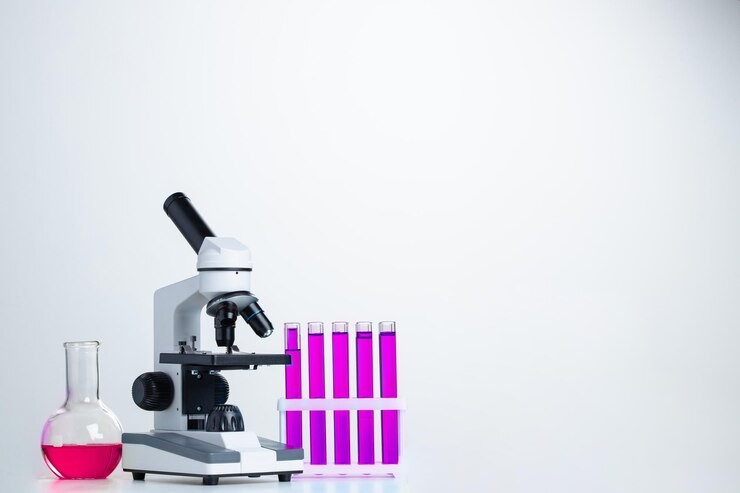 Microscopio de laboratorio con material de vidrio de laboratorio en el escritorio contra el fondo blanco.