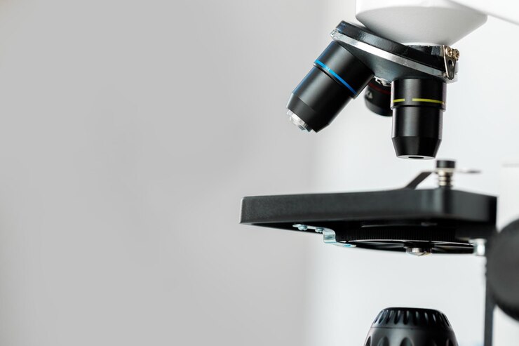 Microscopio en la mesa con cristalería en el laboratorio de cerca
