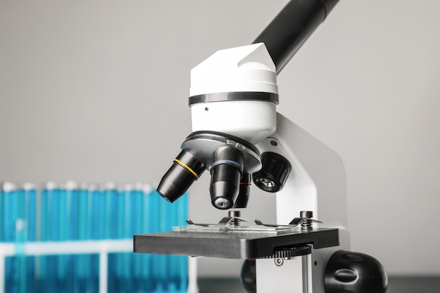 Microscópio moderno e tubos de ensaio na mesa