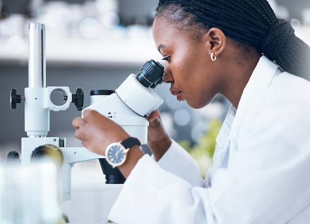 Microscopio mujer negra y ciencia médica en laboratorio para análisis de investigación y medicina Mujer doctora y científica estudian en el trabajo para una investigación sanitaria y futurista o innovación