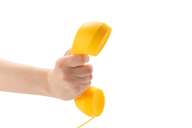Microteléfono amarillo en la mano de la mujer aislada en blanco.