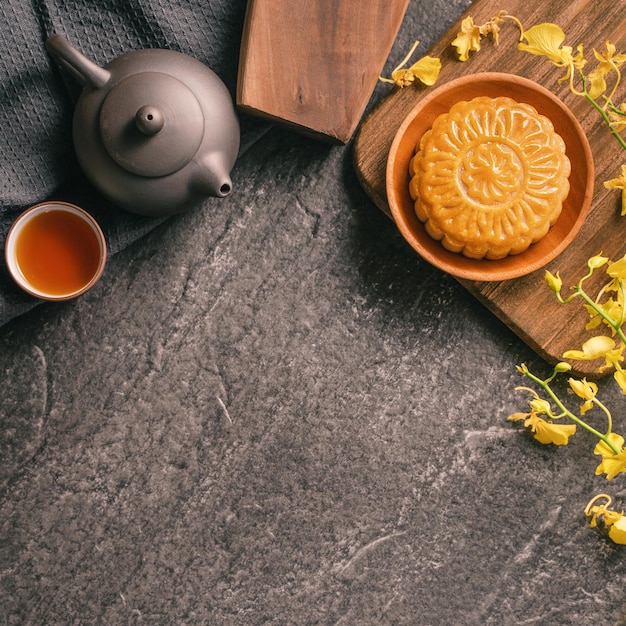 MidAutumn Festival traditionelles Essenskonzept Schöner Mondkuchen auf schwarzem Schiefertisch mit Teegebäck Schimmel Blume Draufsicht flach liegend Kopierraum