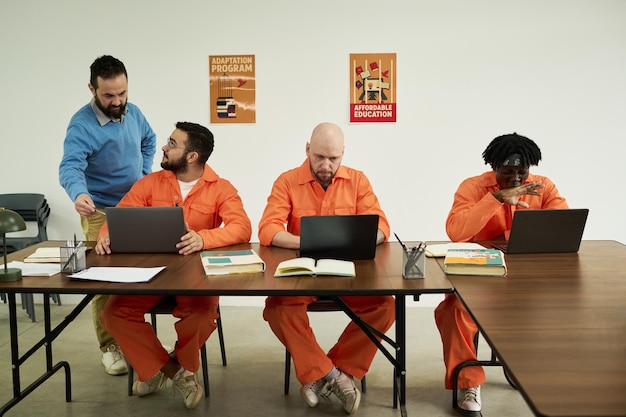 Middle Aged Caucasian Man Teaching Multiethnic Inmates Using Laptops