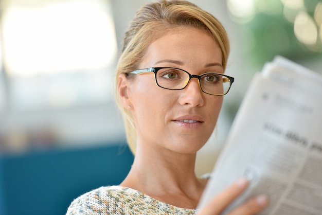 Foto middle-aged, loura, mulher, com, óculos, jornal leitura