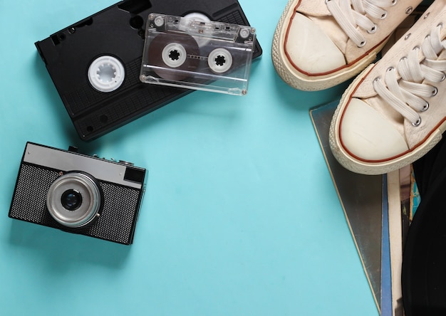 Mídia retro e acessórios em um azul. tênis, cassetes de áudio e vídeo, câmera em um azul