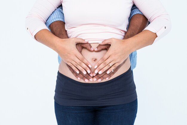 Midsection de casal fazendo forma de coração na barriga