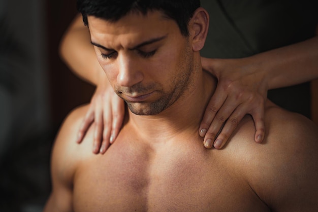 Foto midsection des therapeuten, der einem hemdlosen mann im spa eine massage gibt