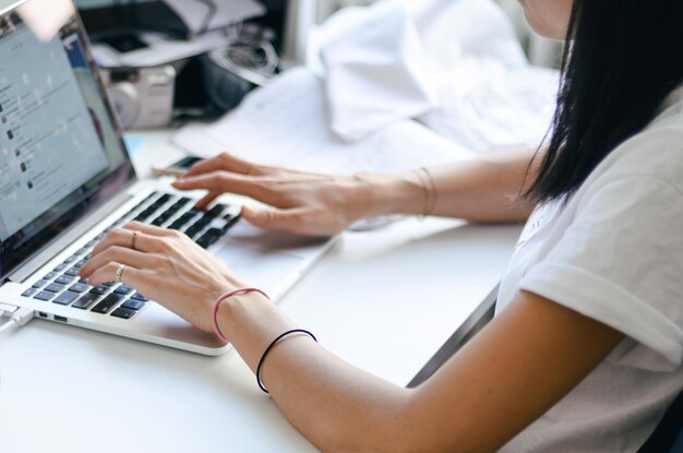 Foto midsection einer frau, die einen laptop am schreibtisch im büro benutzt