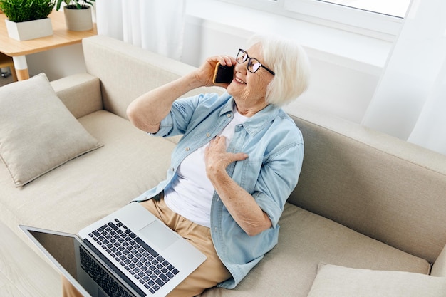 Midsection einer Frau, die zu Hause auf dem Sofa sitzt und einen Laptop benutzt