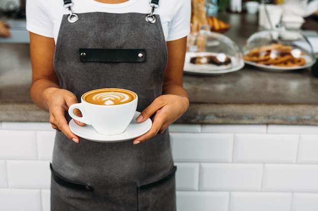 Foto midsection einer jungen frau, die ein kaffeekuppen im café hält