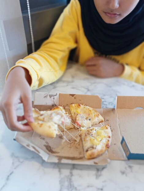 Foto midsection eines mädchens, das pizza im café isst