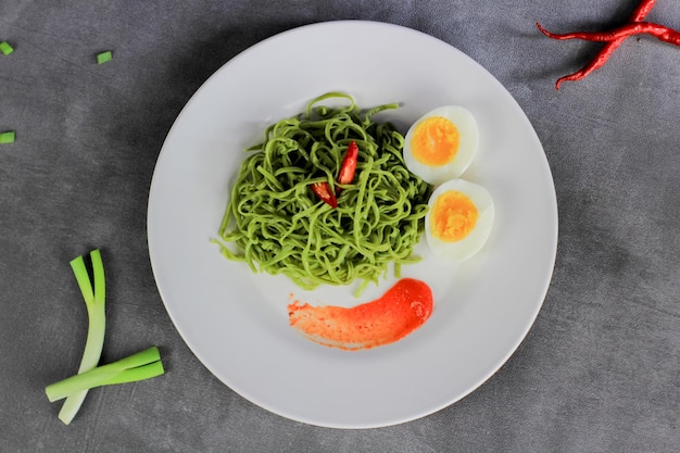 Mie Goreng Gebratene Nudeln, serviert mit Spiegeleiern und Gemüse auf einem Teller