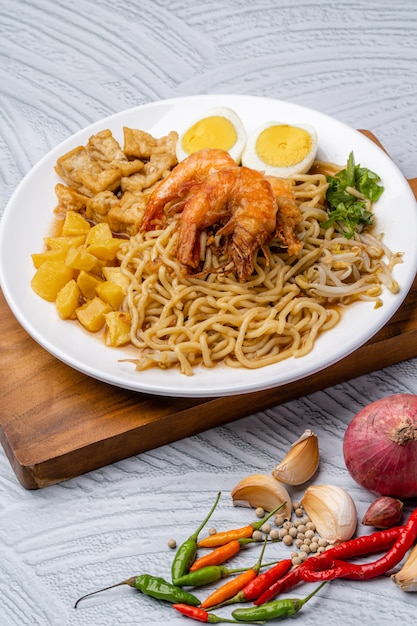 Mie rebus medan o sopa de fideos El plato está hecho de fideos de huevo amarillos que también se usan en Hokkien mee con una salsa picante ligeramente dulce similar al curry La salsa está hecha de caldo de camarones o tauchu