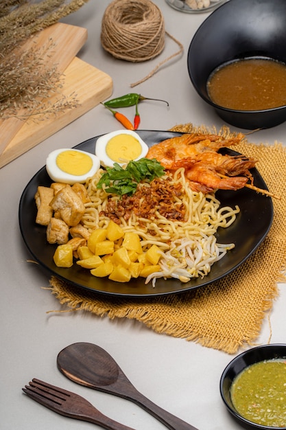 Mie rebus medan ou sopa de macarrão O prato é feito de macarrão de ovo amarelo que também é usado em Hokkien mee com um molho picante ligeiramente doce semelhante ao curry. O molho é feito de caldo de camarão ou tauchu