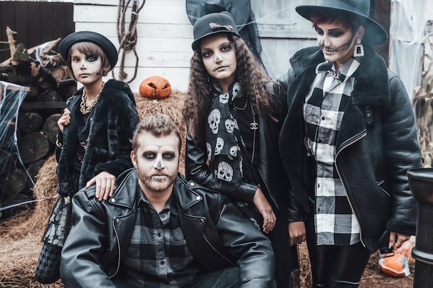 Miedo familia madre padre hijas celebrando Halloween Terrorífico maquillaje de media cara de calavera negra y disfraces de brujas imágenes elegantesHorrorfun at children's party in barn on streetSombreroschaquetas