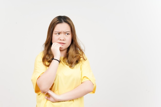 Miedo nervioso y morder las uñas de una hermosa mujer asiática con camiseta amarilla aislada en blanco