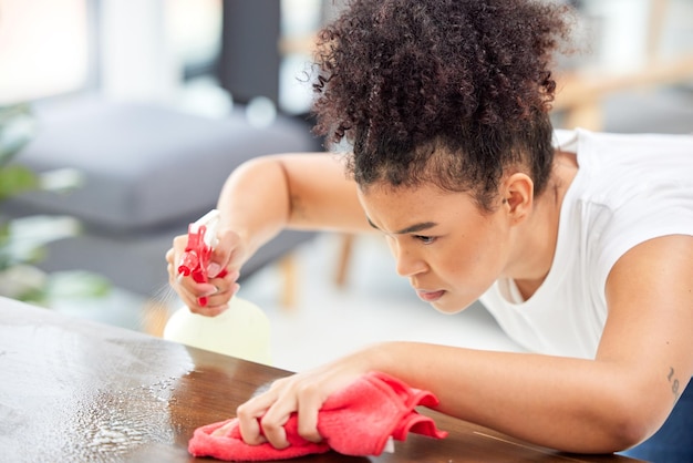 Sin miedo y sin piedad. Foto de una mujer joven limpiando la mesa de café de su sala de estar.