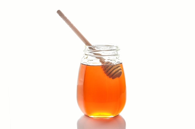 Miel de abeja con una cuchara de madera para miel. aislado