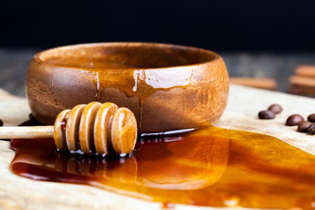 Miel de abeja fresca vertida en una tabla vertida en un plato de madera y miel de miel vertida en una tabla de madera