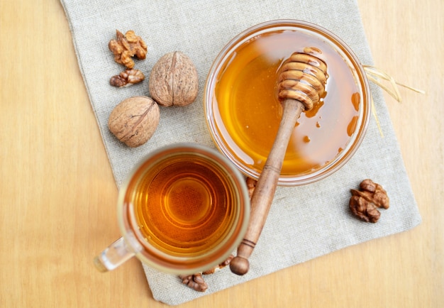 Miel de abeja y té caliente en vaso de vidrio con merienda de nuez en la toalla de cocina. Vista desde arriba