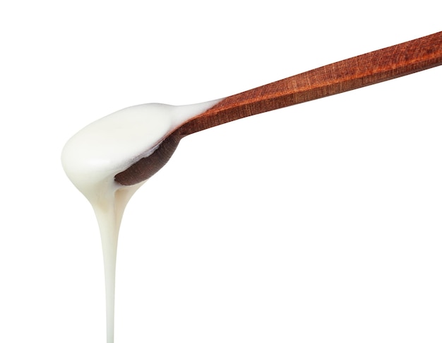 Foto miel blanca saliendo de una pequeña cuchara de madera