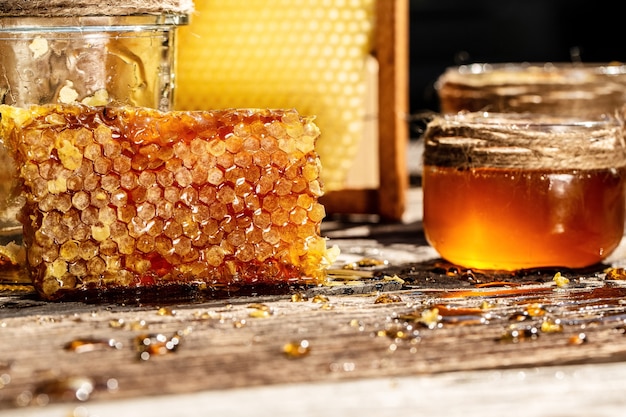 Foto miel dulce en el peine, tarro de cristal con miel sobre fondo de madera