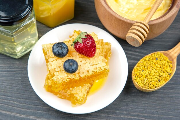 Miel de flores frescas de diferentes variedades, polen y panal con cucharas sobre un fondo de madera. Alimentos saludables con vitaminas orgánicas