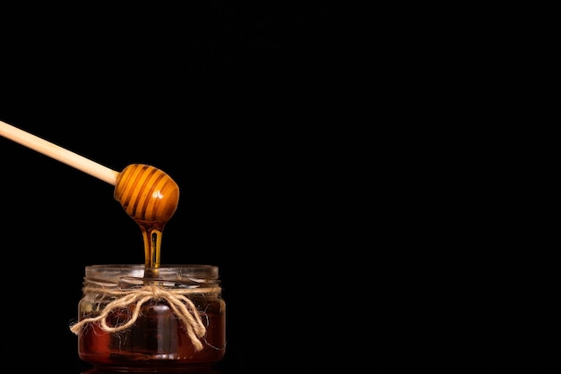 La miel fluye de la cuchara a un frasco de vidrio.