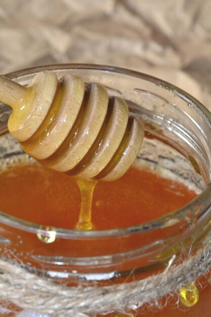 la miel fluye en una jarra de abeja de un palo de madera