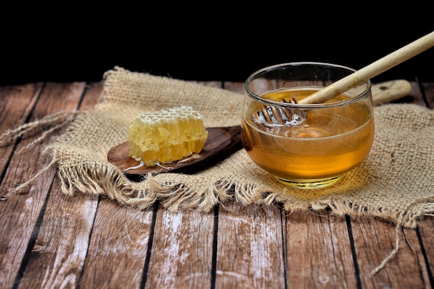 Miel fresca con cucharón de miel de madera en recipiente de vidrio