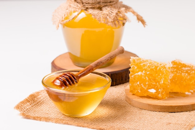 Miel goteando de un cucharón de miel de madera sobre fondo blanco. Concepto de comida orgánica saludable.