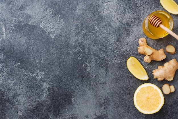 Miel de limón y raíz de jengibre sobre superficie gris oscuro