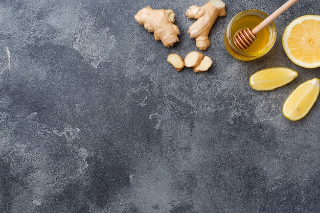 Miel de limón y raíz de jengibre sobre superficie gris oscuro