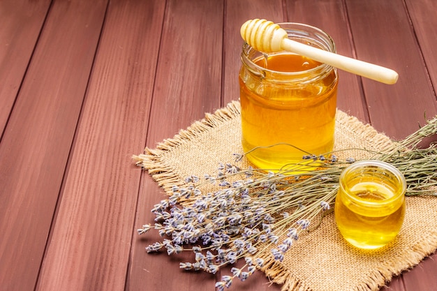 Miel líquida fresca en frascos de vidrio con un cucharón de madera