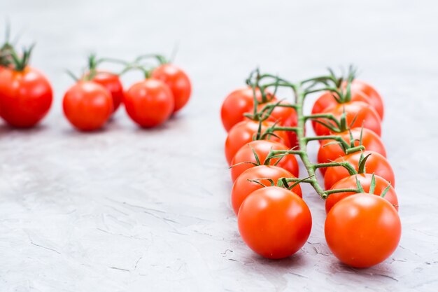 Miel maduras tomates cherry en una rama sobre un fondo de hormigón