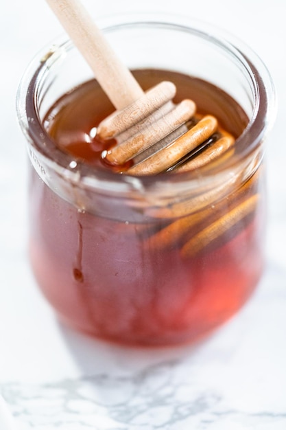 Miel orgánica en un pequeño tarro de cristal con cucharón de madera.
