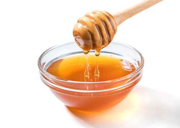 Miel que gotea del cucharón de miel sobre una superficie blanca. Miel espesa de la cuchara de miel de madera. Concepto de comida sana.