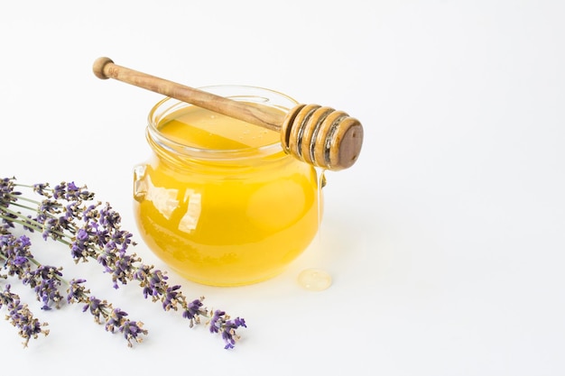 Miel en el tarro de cristal y flor de lavanda en el fondo blanco Primer espacio de copia