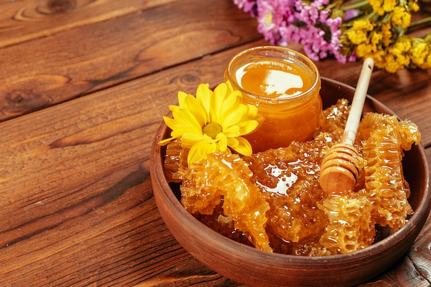 Miel en tarro con cucharón de miel sobre fondo de madera vintage