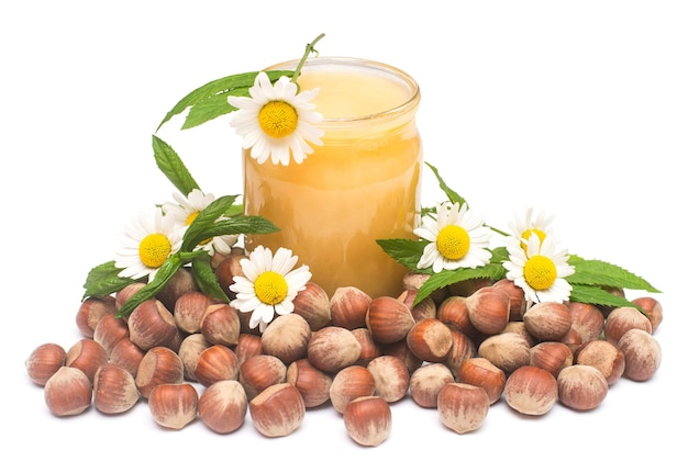 Miel en tarro con menta, nueces y flor de manzanilla aislado sobre fondo blanco. Farmacia verde. Alimento amarillo y saludable para la salud y el deporte. Vitaminas