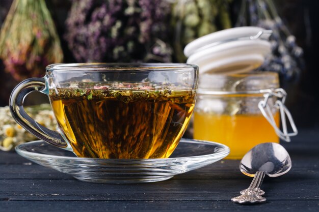 Miel con té sobre fondo de mesa rústica con hierbas